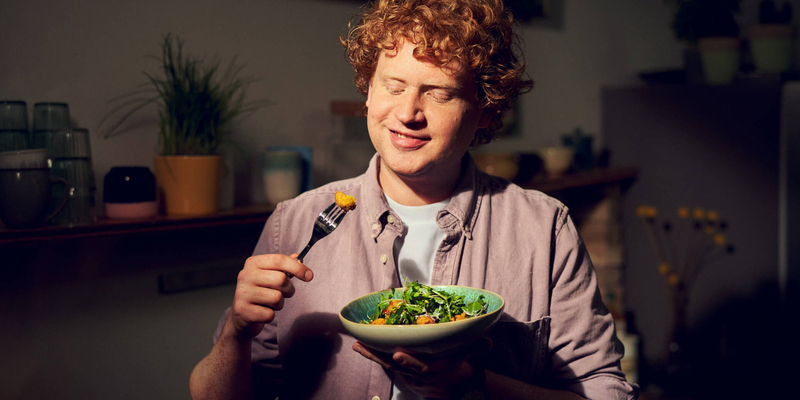 Ein Mann isst genüsslich einen Salat mit veganen Falafeln.