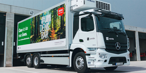 Ein E-Lkw des Transportunternehmens Einride. Auf der Seite sieht man REWE Werbung mit dem Text „Clean ist das neue Green. #UMDENKBAR“.