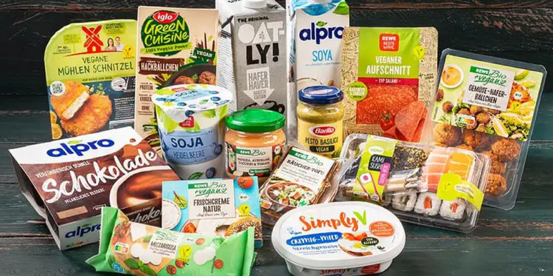 Auswahl veganer Produkte im Hintergrund und Logo von dem 'Vegan Food Award' im Vordergrund