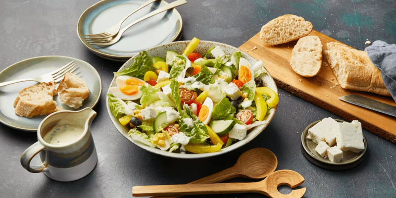 Teller mit grünem Salat und weiteren Küchenutensilien drumherum