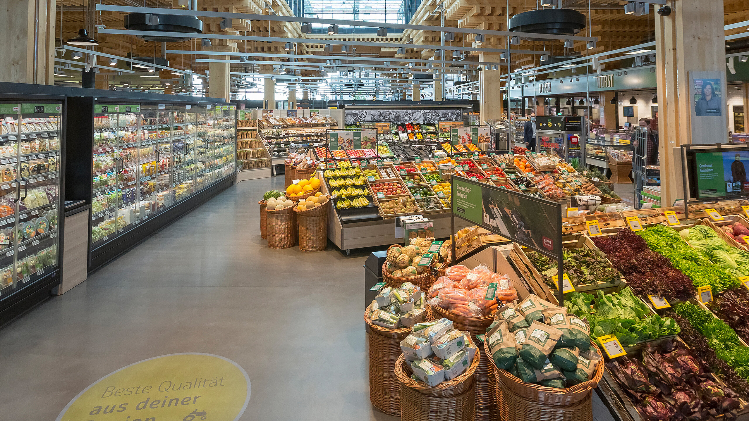 Ein Blick aus der Obst- und Gemüseabteilung in einen nachhaltigeren REWE Markt. 