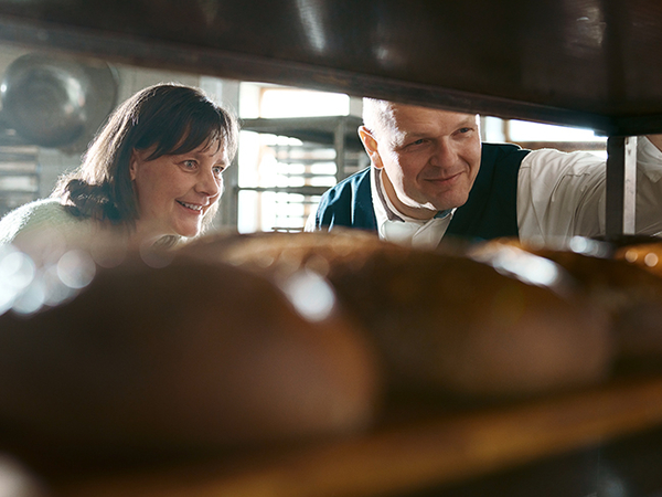 Sophia Sucholas und Björn Keyser betrachten frische Brote in der Bäckerei.