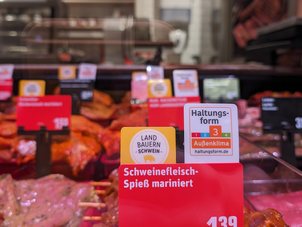 Landbauern Schweinefleisch an der Bedientheke in einem REWE Markt. Die Schildchen an der Theke zeigen das Landbauern Logo. 