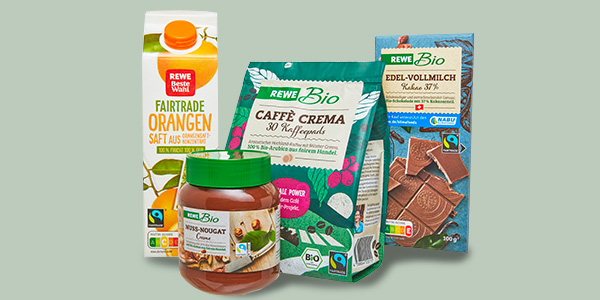 Mehrere Fairtrade Produkte: REWE Beste Wahl Fairtrade Orangensaft, REWE Bio Nuss-Nougat-Creme, REWE Bio Caffè Crema und eine Tafel REWE Bio Schokolade Edel-Vollmilch.  