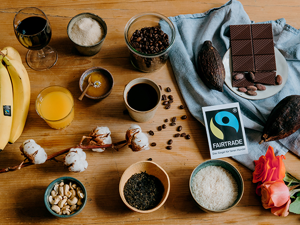 Auf einem Holtisch liegen verschiedene fair gehandelte Lebensmittel sowie das Fairtrade-Logo