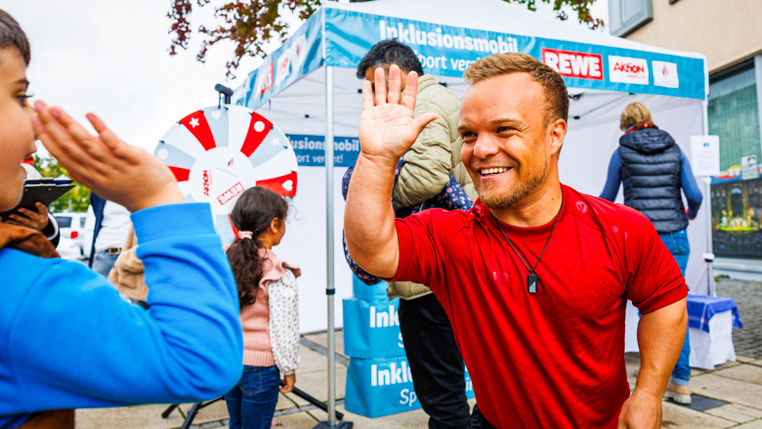 Para-Kugelstoßer Niko Kappel gibt einem Jungen High Five.