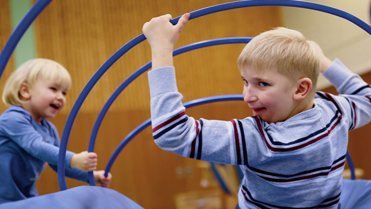 Zwei Kinder probieren spielerisch ein inklusives Turngerät aus. 