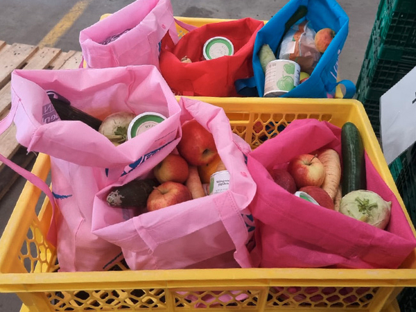 Man sieht eine Kiste mit mehreren gepackten Lebensmittel-Tüten die an Bedürftige verteilt werden.