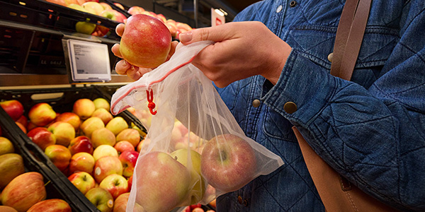 Eine Person legt unverpackte Äpfel in ein Mehrweg-Frischenetz. 